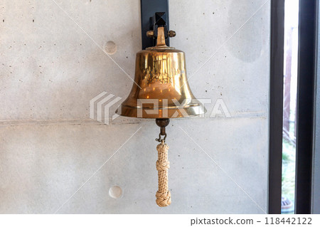 Brass bell on a gray wall indoors. Brass bell on a gray wall indoors. 118442122