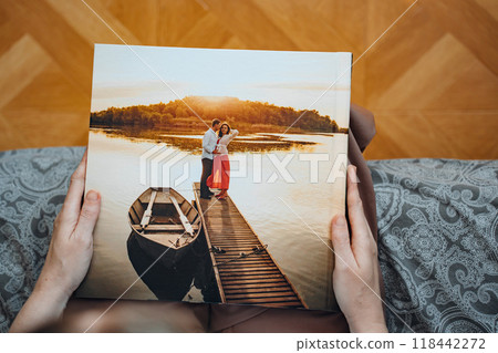 woman is holding and flipping through a photo book with a pregnancy photo shoot woman is holding and flipping through a photo book with a pregnancy photo shoot 118442272