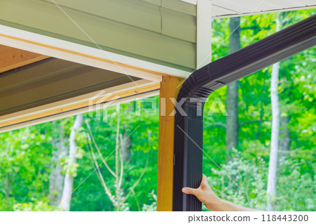 It is handyman who is assembling gutter channel on roof with help of ladder It is handyman who is assembling gutter channel on roof with help of ladder 118443200