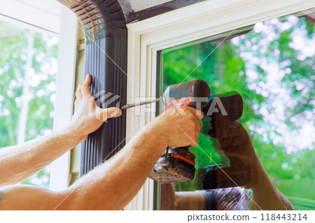 Handyman is assembling gutter channel that is attached to roof with installation of gutter Handyman is assembling gutter channel that is attached to roof with installation of gutter 118443214