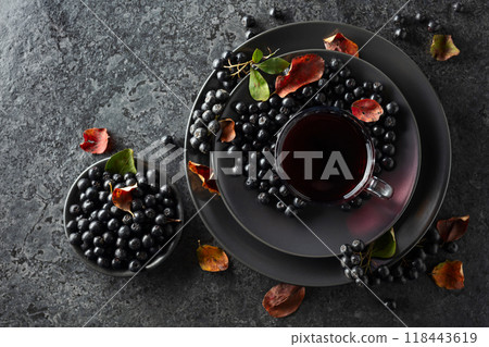 Black chokeberry drink and fresh berries on a black stone table. 118443619
