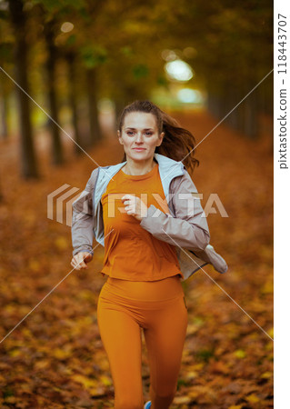 trendy 40 years old woman in fitness clothes in park running trendy 40 years old woman in fitness clothes in park running 118443707