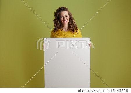 smiling healthy female showing blank board against green smiling healthy female showing blank board against green 118443828
