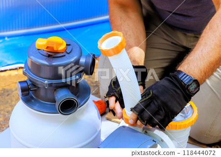 Maintenance worker assembles sand filter system tank well as cleaning equipment for swimming pools 118444072