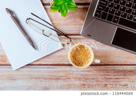 Workspace with laptop, coffee, pen, and notebook on top of an office table Workspace with laptop, coffee, pen, and notebook on top of an office table 118444089