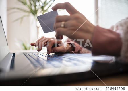 Low angle closeup view of female hands holding a credit card paying online 118444208