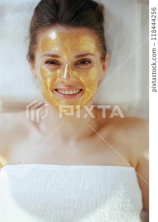 smiling modern female in spa salon laying on massage table 118444256