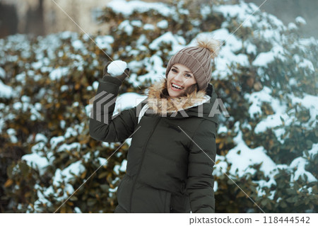 happy woman outdoors in park in winter throwing snowballs 118444542