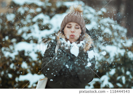 40 years old woman outdoors in park in winter blowing snow 40 years old woman outdoors in park in winter blowing snow 118444543