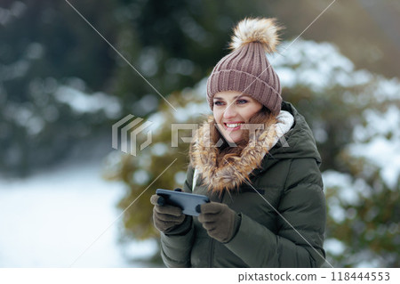 happy woman outdoors in park in winter using smartphone app happy woman outdoors in park in winter using smartphone app 118444553