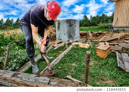 To lower concrete ring into pit during septic tank installation, worker uses winch. 118445655