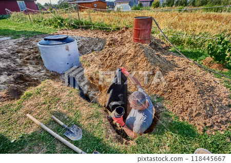 Laying drainage fabric and perforated pipe in an absorption trench for wastewater plumbing. 118445667