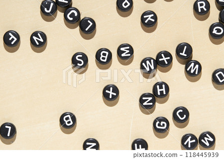 Scattered black alphabet letter beads on beige background for creative education Scattered black alphabet letter beads on beige background for creative education 118445939