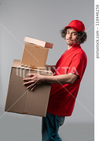 Postal courier man with heavy parcels boxes. Postman delivers address package on white studio background. 118446256