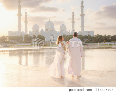Travel to the United Arab Emirates, Abu Dhabi. Arab couple visiting park near Grand Mosque in Abu Dhabi wearing traditional dress. Travel to the United Arab Emirates, Abu Dhabi. Arab couple visiting park near Grand Mosque in Abu Dhabi wearing traditional dress. 118446492
