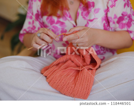 Young Woman knitting scarf in living room. doing crochet knits. Young Woman knitting scarf in living room. doing crochet knits. 118446501