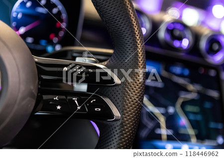 Close-up shot of a luxury car steering wheel featuring control buttons and sleek leather details Close-up shot of a luxury car steering wheel featuring control buttons and sleek leather details 118446962