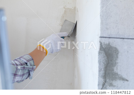The concept of leveling the corner of a wall using a corner trowel. 118447812