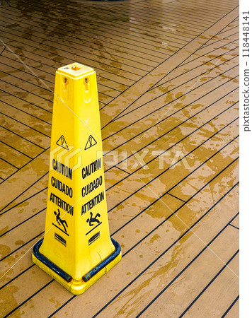 A yellow plastic warning pylon about the slippery wet floor on the deck of a cruise ship A yellow plastic warning pylon about the slippery wet floor on the deck of a cruise ship 118448141