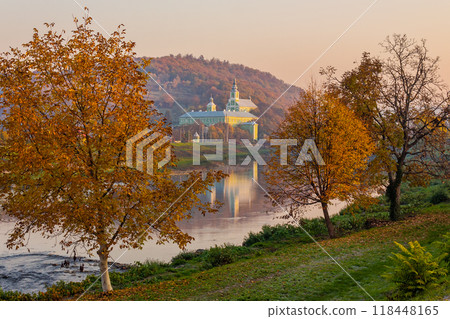 mukachevo, ukraine - 06 nov 2015: old town with latorica river in autumn. embankment with trees in fall season. saint nicholas monastery in the distance. urban scenery in morning light 118448165