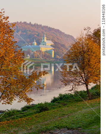 mukachevo, ukraine - 06 nov 2015: old town with latorica river in autumn. embankment with trees in fall season. saint nicholas monastery in the distance. urban scenery in morning light 118448166