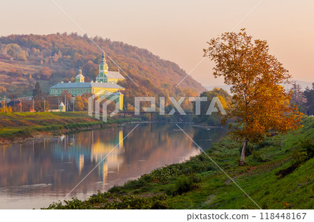 mukachevo, ukraine - 06 nov 2015: old town with latorica river in autumn. embankment with trees in fall season. saint nicholas monastery in the distance. urban scenery in morning light mukachevo, ukraine - 06 nov 2015: old town with latorica river in autumn. embankment with trees in fall season. saint nicholas monastery in the distance. urban scenery in morning light 118448167