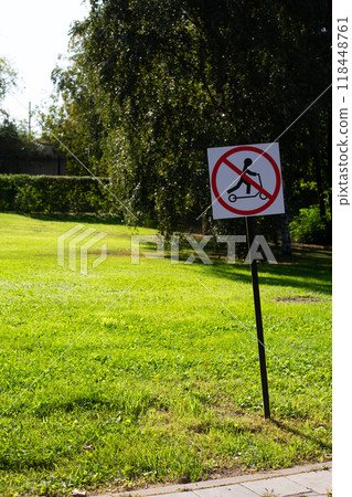 Sign in the park prohibits riding scooter. Road sign regulating traffic on city street. Modern rules for scooters in green field background 118448761