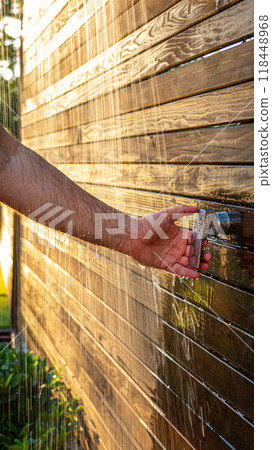Man uses outdoor shower at sunset. Concept of summer rest Man uses outdoor shower at sunset. Concept of summer rest 118448968