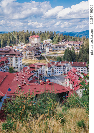 Scenic view of resort buildings with red roofs nestled in mountains, sunny day in tranquil forested area 118449005