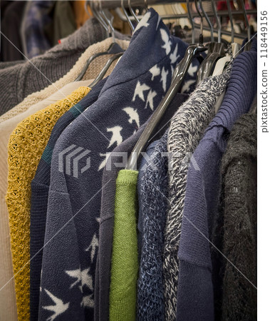 Colorful sweaters hanging in a thrift store for reuse and recycling awareness 118449156