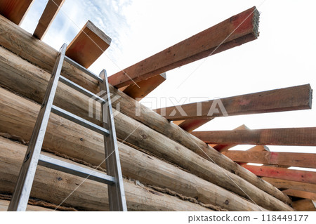 Rural wooden house house is under construction. A ladder goes up to the wall Rural wooden house house is under construction. A ladder goes up to the wall 118449177