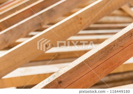 Wooden house roof is under construction. Rafters and beams are in a row Wooden house roof is under construction. Rafters and beams are in a row 118449180