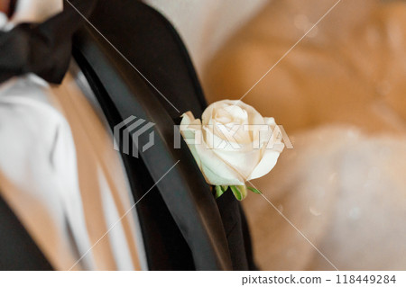 Elegant White Rose Boutonniere on Classic Black Tuxedo in a Romantic Wedding Setting 118449284