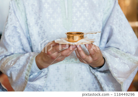 Clerical Hands Holding Golden Chalice in Spiritual Ceremony 118449296