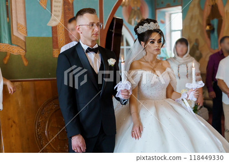 Elegant Wedding Ceremony in a Traditional Venue with Bride and Groom Holding Candles 118449330