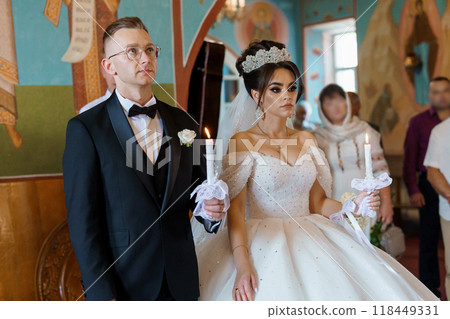 Elegant Church Wedding Ceremony with Bride and Groom Holding Candles in Traditional Attire 118449331