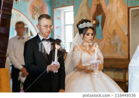 Elegant Orthodox Wedding Ceremony in Traditional Church Setting Captured with Candlelit Ambiance 118449336