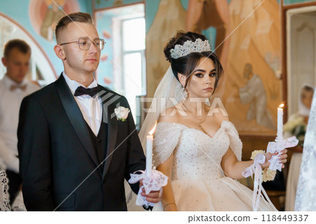 Elegant Wedding Ceremony with Bride and Groom Holding Candles in Ornate Church Setting 118449337