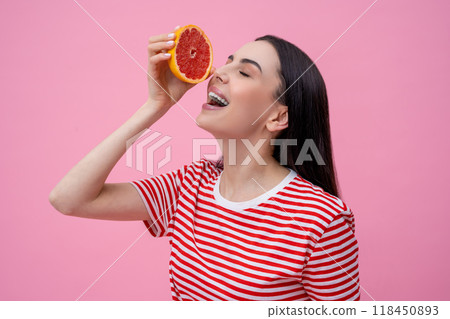 Pretty happy young woman in striped tshirt with part of grapefruit in hand 118450893