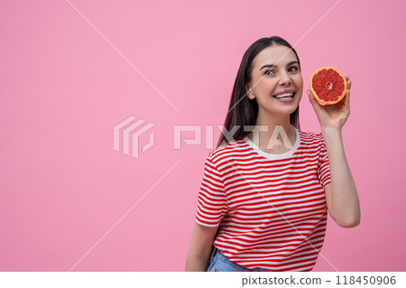 Pretty happy young woman in striped tshirt with part of grapefruit in hand 118450906