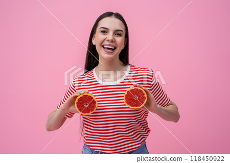 Cute smiling young woman holding slices of grapefruit in hands Cute smiling young woman holding slices of grapefruit in hands 118450922