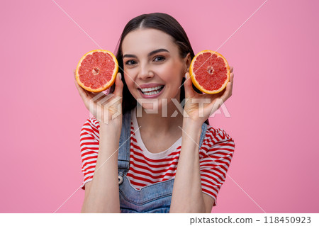 Cute smiling young woman holding slices of grapefruit in hands Cute smiling young woman holding slices of grapefruit in hands 118450923