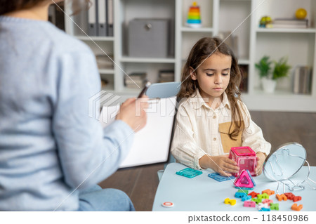 Cute little girl sitting at the table and having a training session with speech therapist 118450986