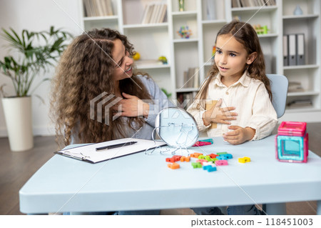 Good-looking young speech therapist working with a cute girl on her articulation 118451003
