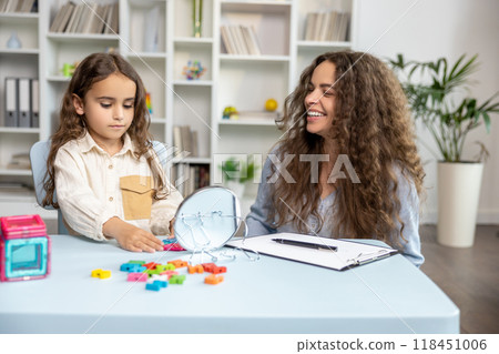 Good-looking young speech therapist working with a cute girl on her articulation 118451006
