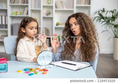 Child and doctor working on articulation and looking contented and concentrated Child and doctor working on articulation and looking contented and concentrated 118451020