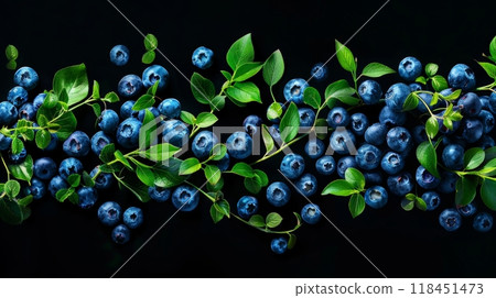 Rich, plump blueberries are elegantly arranged with lush green leaves, creating a striking contrast against a dark backdrop. This composition highlights the freshness and appeal of nature 118451473