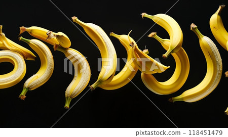 A dynamic arrangement of bananas appears to float gracefully, curving and swirling elegantly against a dark background, showcasing their bright yellow hues and natural forms 118451479