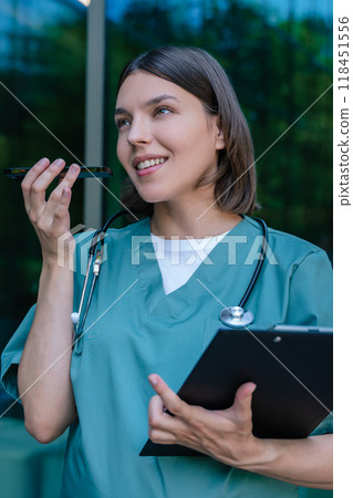 Pretty pregnant woman in a lab coat recording a voice message Pretty pregnant woman in a lab coat recording a voice message 118451556