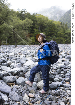 A woman climbing a mountain wearing a raincoat 118453668